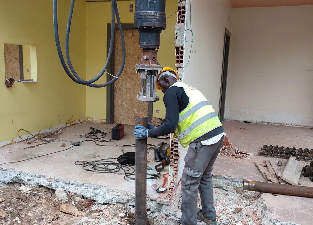 Installing a helical pile in the tight space beneath the building